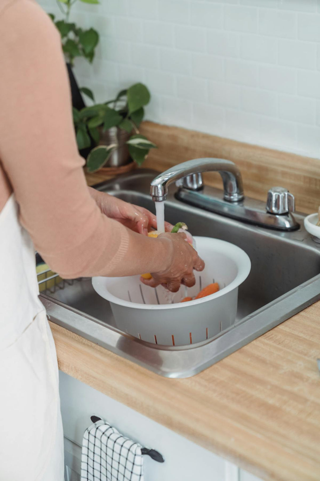 Over-the-Sink Expandable Cutting Board with Built-In Colander — rinsing vegetables over the sink